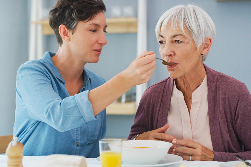 Isnt this delicious Mum. an attractive young woman helping and feeding her senior mother while they have breakfast together at home