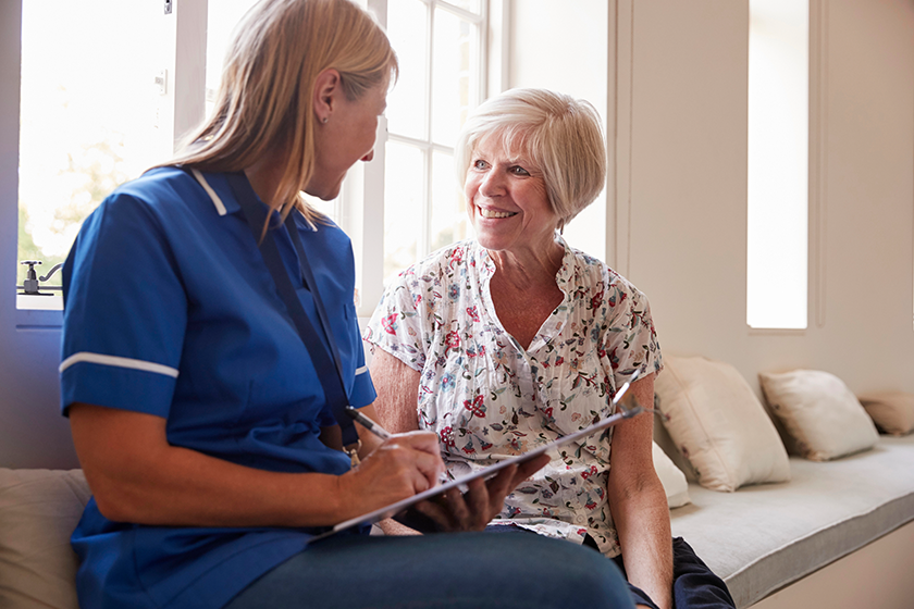 senior-woman-sits-nurse-making-notes